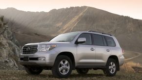 A light metallic 2008 Toyota Land Cruiser parked in front of a green mountain in left front angle view