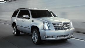 A light silver 2014 Cadillac Escalade driving in right front angle view