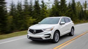 A white 2021 Acura RDX driving in left front angle view