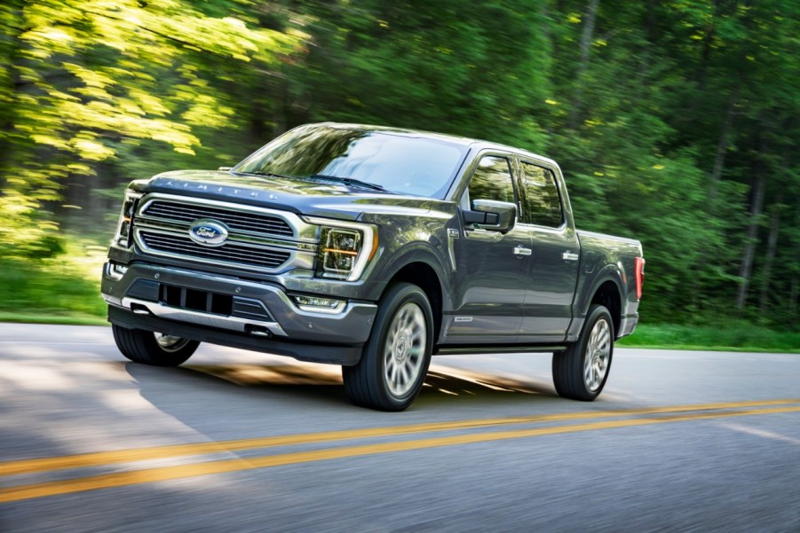 A 2021 Ford F-150 driving on a two-lane road in left front angle view