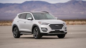 A white Hyundai Tucson parked outside on flat ground in right front angle view