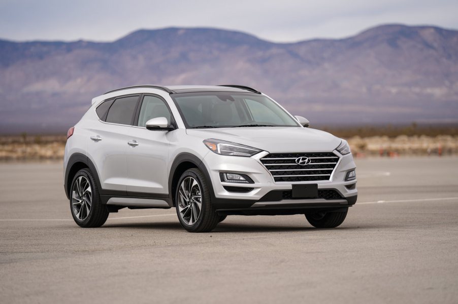 A white Hyundai Tucson parked outside on flat ground in right front angle view