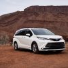 A white 2021 Toyota Sienna parked in right front angle view in a rocky, dusty clay desert environment