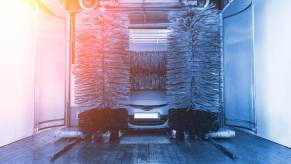 A car and a minivan drive through a touch car wash.