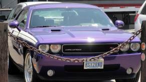 Purple 2009 Dodge Challenger R/T parked in San Francisco lot, a chain visible in the background.