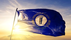 Blue flag that says "commonwealth of Kentucky" with the sun in the background.