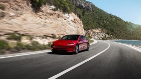 A post-update Tesla Model 3 "Highland" drives around a corner.