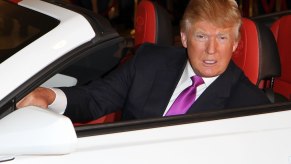 Donald Trump sitting in a white Chevrolet Camaro convertible with a red interior.