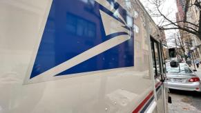 A USPS mail truck on a city street.