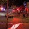 A Waymo self-driving car drives up a road near police and fire vehicles.