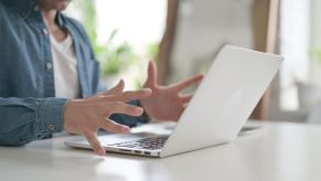 A man writing an angry email, expressing frustration with his hands