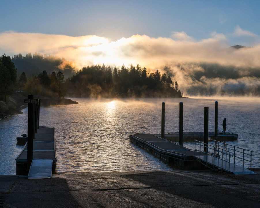 Boat ramp at a lake in the evening with fog settling in the evergreen trees across the water