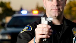 A police officer holding a breathalyzer to a driver to determine if they're driving drunk