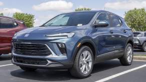 A blue Buick Encore SUV parked at a dealership lot in close left front angle view