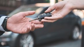 A car selling handing a car buyer the keys to a car after a sale was completed