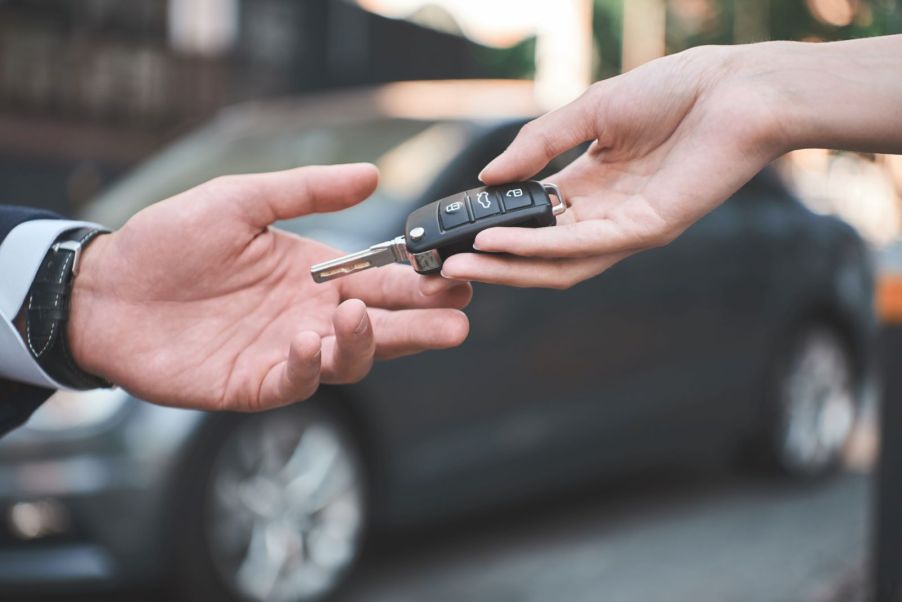 A car selling handing a car buyer the keys to a car after a sale was completed