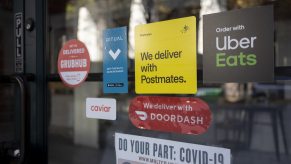 DoorDash sticker plus other food delivery services on a retail storefront glass door