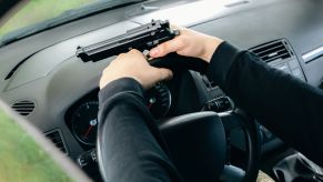 A man driving while holding a gun in the driver's seat police