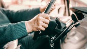 Elderly person's hands driving a car in close side view