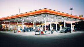 A well-lit gas station at night with cars pumping gas