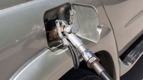 A gas pump nozzle in the gas tank of a modern SUV