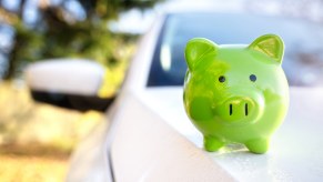 Green piggy bank sitting on car hood representation of an auto loan