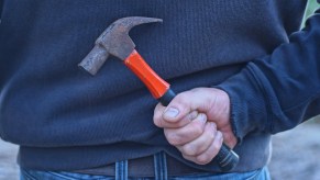 A man holding a hammer behind his back