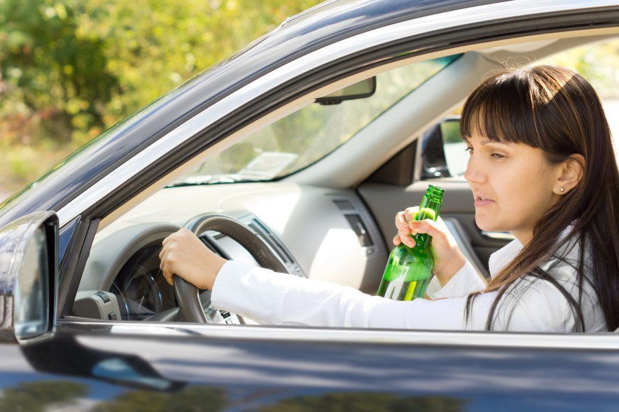 A woman drinking a beer while driving