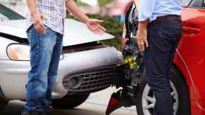 Two drivers talking in front of their crashed cars as a result of being rear ended