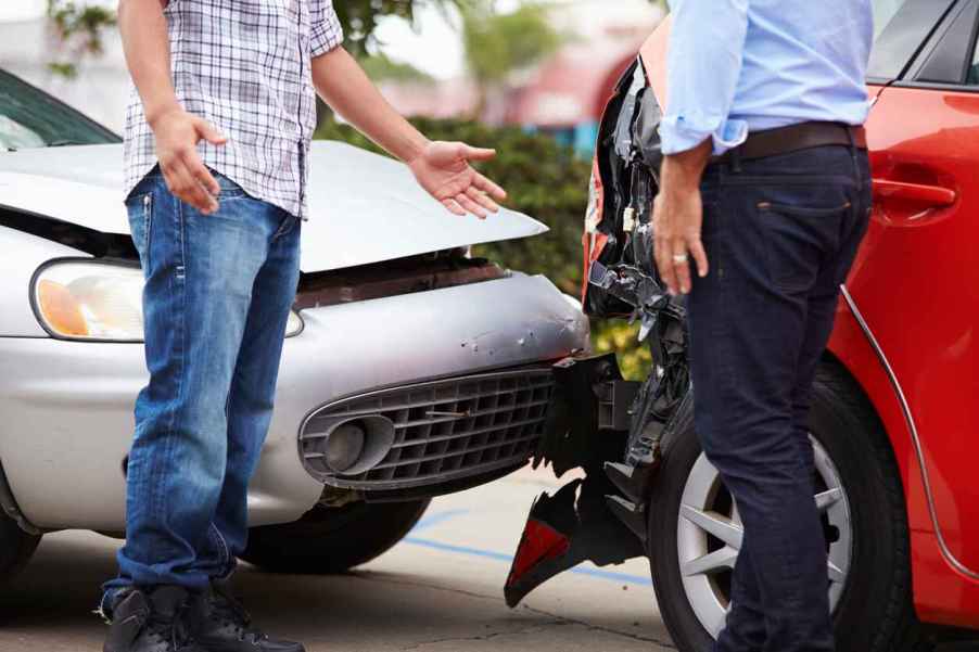 Two drivers talking in front of their crashed cars as a result of being rear ended