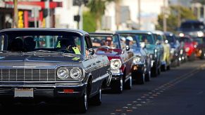 A group of lowrider cars heading to a car show