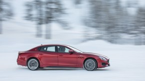 A red Maserati Quattroporte driving in the snow, the car is one of the fastest-depreciating cars on the market