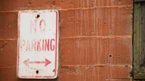 A sign on a brick wall that reads, "No Parking."