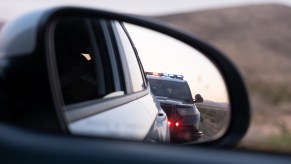 A car pulled over looking at police SUV in the side view mirror