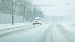 A police car driving in the snow responding to a call