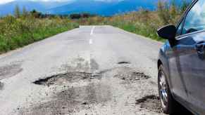 A car traveling down the road running over a large pothole