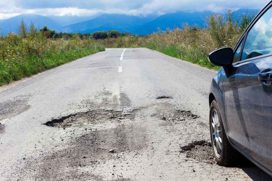 A car traveling down the road running over a large pothole