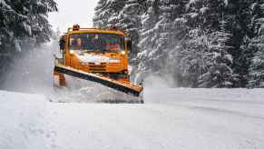 A snow plow removing snow on a snowy road