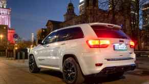 A Jeep Grand Cherokee Trackhawk driving on a public road at night with the taillights illuminated