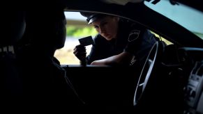 A pensive looking female police officer checking the license of a driver they just pulled over