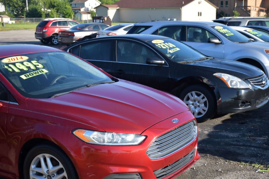 Cars sitting in a parking lot of a used car dealership