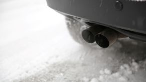 A car warming up on a cold winter's morning, with exhaust coming from the tailpipe