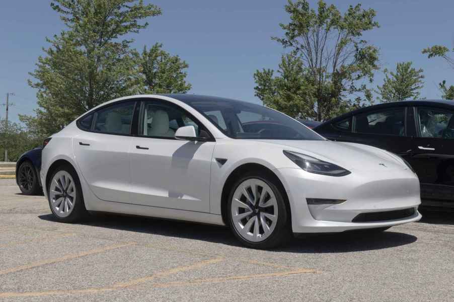 A white Tesla EV parked in right front angle view