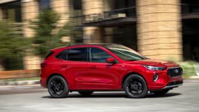 A red Ford Escape ST, an American SUV, takes a corner on a city street.