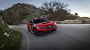 A red Subaru WRX driving fast on a curvy hilly road