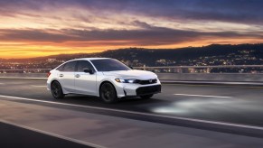 A white 2025 Honda Civic driving at dusk