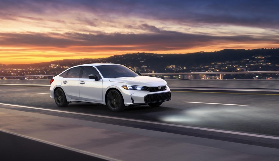 A white 2025 Honda Civic driving at dusk