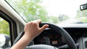 A driver with incorrect hand placement committing one of the most common driving mistakes.