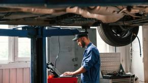 Mechanics working at a shop using a plug-in module for a car on a lift.