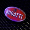 The red "Bugatti" badge on the grille of a supercar.